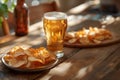 A glass of beer and a plate of chips sit on a wooden table Royalty Free Stock Photo