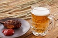 Glass of beer, plate with grilled chicken and ears of barley on a wooden background Royalty Free Stock Photo