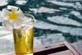 A glass of beer with plumeria flower on wooden chair in swiming pool Royalty Free Stock Photo