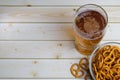 Glass of beer and salty mini pretzels in a deep glass bowl on a wooden tabletop Royalty Free Stock Photo