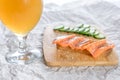 Glass of beer and sandwiches with bread, fresh fish and sliced cucumbers with spices on wooden tray Royalty Free Stock Photo