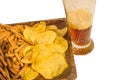 A glass of beer with a snack of rye crackers and chips on a dark wooden plate, isolated on a white background by clipping Royalty Free Stock Photo