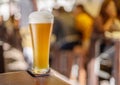 Glass of beer stands on a table in a pub. White unfiltered beer