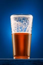 a glass of beer on a wooden stand and a dark blue background, pouring beer into a glass, a close view of the object, the beer Royalty Free Stock Photo