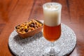 Glass of Belgian light blond beer made in abbey and bowl with party mix nuts Royalty Free Stock Photo