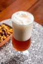 Glass of Belgian light blond beer made in abbey and bowl with party mix nuts Royalty Free Stock Photo