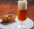 Glass of Belgian light blond beer made in abbey and bowl with party mix nuts Royalty Free Stock Photo