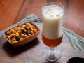 Glass of Belgian light blond beer made in abbey and bowl with party mix nuts Royalty Free Stock Photo