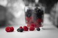 The glass with berries is out of focus, the foreground, on which the berries are scattered, is in focus.