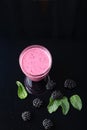 Glass of blackberry milkshake on black background. Healthy drink. Top view.