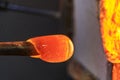 Glass blower working on a bubble of melted glass on a rod by heating it up in a kiln at a glass maker& x27;s workshop Royalty Free Stock Photo