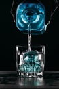 Glass with blue ice cubes. Pouring gin into a glass on a wooden table. Gin in a glass on a black background Royalty Free Stock Photo