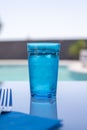 glass of blue water in front of the pool, summer image, pastel colors Royalty Free Stock Photo