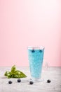 Glass of blueberry blue colored drink with basil seeds on a gray and pink background.  Side view Royalty Free Stock Photo