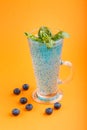 Glass of blueberry blue colored drink with basil seeds on orange background. Morninig, spring, healthy drink concept. Side view Royalty Free Stock Photo