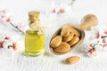 Glass bottle of Almond oil and almond nuts , almonds with almond tree flowers on table