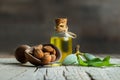 Glass bottle of Almond oil and almond nuts in wooden shovel with green fresh raw almonds on wooden table Royalty Free Stock Photo