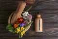 Glass bottle of aromatic essential oil and mortar with different herbs on wooden table, flat lay. Space for text Royalty Free Stock Photo