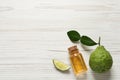 Glass bottle of bergamot essential oil and fresh fruit on white wooden table, flat lay. Space for text Royalty Free Stock Photo