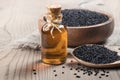 Glass bottle of black cumin seeds essential oil , Nigella Sativa in spoon on wooden background