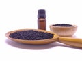 Glass bottle of black cumin seeds essential oil , Nigella Sativa in wooden spoon and bowl on white background. Concept of herbal Royalty Free Stock Photo