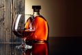 Glass and bottle of brandy on a black reflective background Royalty Free Stock Photo