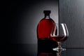 Glass and bottle of brandy on a black reflective background Royalty Free Stock Photo