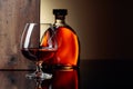 Glass and bottle of brandy on a black reflective background Royalty Free Stock Photo