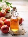 Glass bottle with cider vinegar and ripe apples on light wooden background, close-up, Rustic style, vertical image