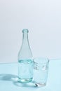 A glass bottle with clear water and a glass on a white-blue background. Minimalistic creative concept Royalty Free Stock Photo