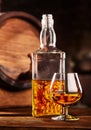 Glass and bottle of Cognac on wodden table old oak barrel defocussed Royalty Free Stock Photo
