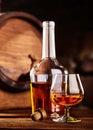 Glass and bottle of Cognac on wodden table old oak barrel defocussed Royalty Free Stock Photo