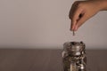 A glass bottle with a coin full on the wooden floor And the man's hand was putting the coin down Royalty Free Stock Photo