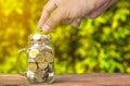 A glass bottle with a coin full on the wooden floor And the man's hand was putting the coin down. Royalty Free Stock Photo