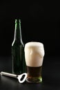 Glass and bottle of cold beer with opener on dark background Royalty Free Stock Photo