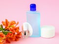 Glass bottle with colorless nail polish, plastic bottle with nail varnish remover, cotton pads and orange flowers on a pastel pink Royalty Free Stock Photo