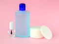 Glass bottle with colorless nail polish, plastic bottle with nail varnish remover and cotton pads on a pastel pink background. Royalty Free Stock Photo