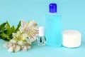 Glass bottle with colorless nail polish, plastic bottle with nail varnish remover, cotton pads and white flowers on a blue Royalty Free Stock Photo