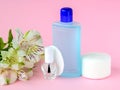 Glass bottle with colorless nail polish, plastic bottle with nail varnish remover, cotton pads and white flowers on a pastel pink Royalty Free Stock Photo