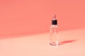 Glass bottle cosmetic serum delicate coral background