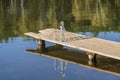 Glass and bottle with drinking water on a wooden pier in the morning near the lake. Nature and travel concept Royalty Free Stock Photo