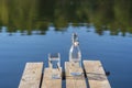 Glass and bottle with drinking water on a wooden pier in the morning near the lake. Nature and travel concept Royalty Free Stock Photo