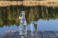 Glass and bottle with drinking water on a wooden table in the morning near the lake. Nature and travel concept Royalty Free Stock Photo