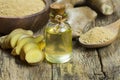 Glass bottle of essential ginger oil, ginger root and powder on wooden rustic background Royalty Free Stock Photo