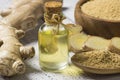 Glass bottle of essential ginger oil, ginger root and powder on wooden rustic background