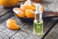 A glass bottle of essential oil with mandarin and slices of ripe mandarin are on the table Royalty Free Stock Photo