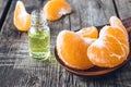A glass bottle of essential oil with mandarin and slices of ripe mandarin are on the table Royalty Free Stock Photo