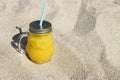 Glass bottle with fresh fruit juice standing on sandy beach. concept of summer holidays Royalty Free Stock Photo