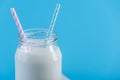 Glass bottle of fresh milk with two straws on blue background. Colorful minimalism. Healthy dairy products with calcium Royalty Free Stock Photo