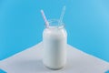 Glass bottle of fresh milk with two straws on blue background. Colorful minimalism. Healthy dairy products with calcium Royalty Free Stock Photo